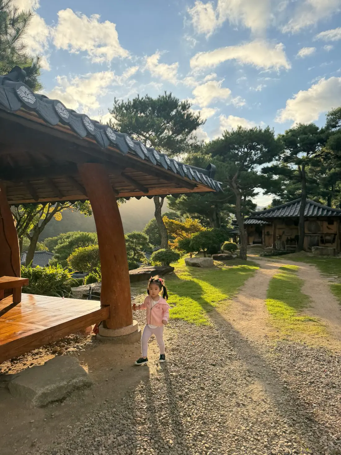 해 질 무렵 정자 옆 흙길에 서 있는 아이